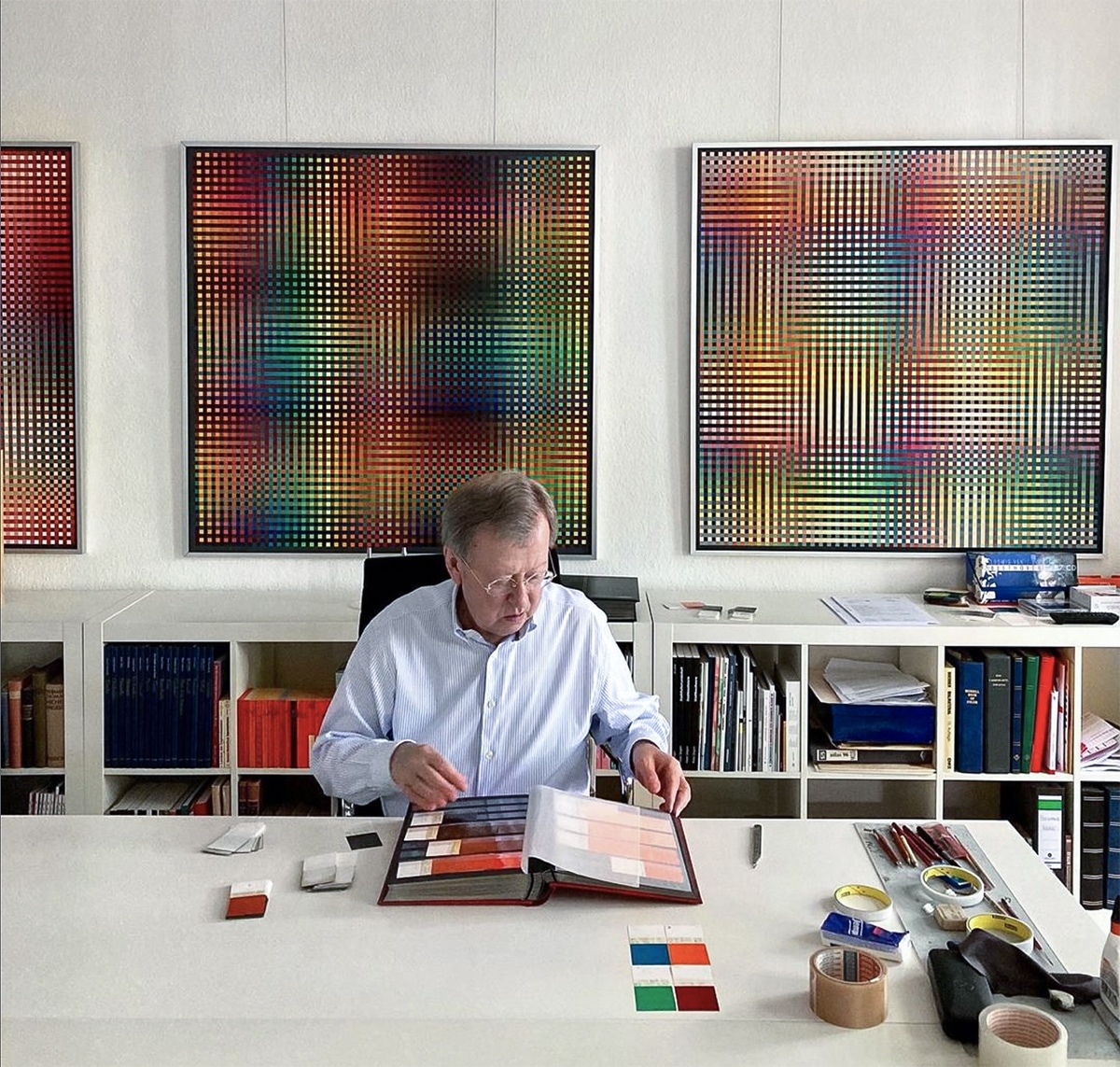 Carl Krasberg picking color cards in his studio surrounded by concrete paintings
