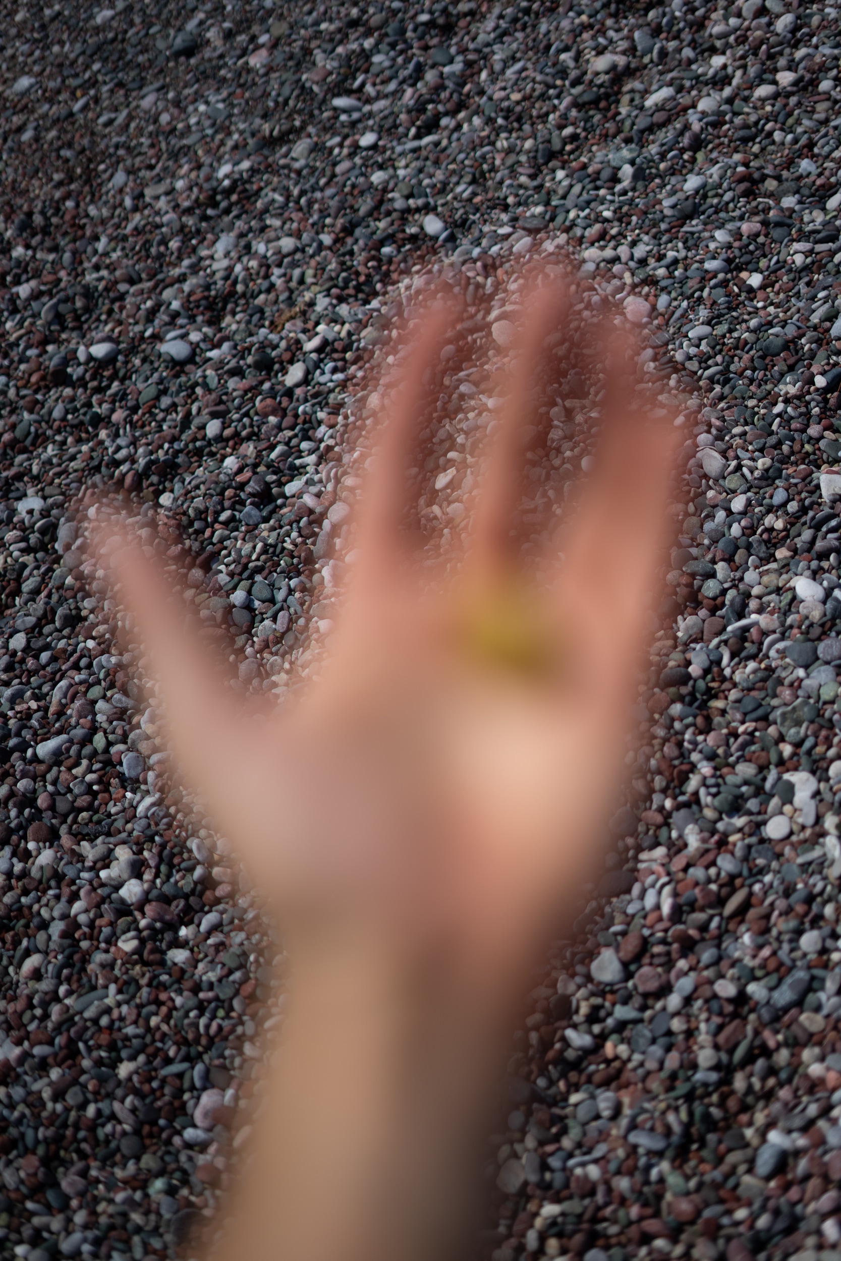 My hand out of focus in front of beach stones